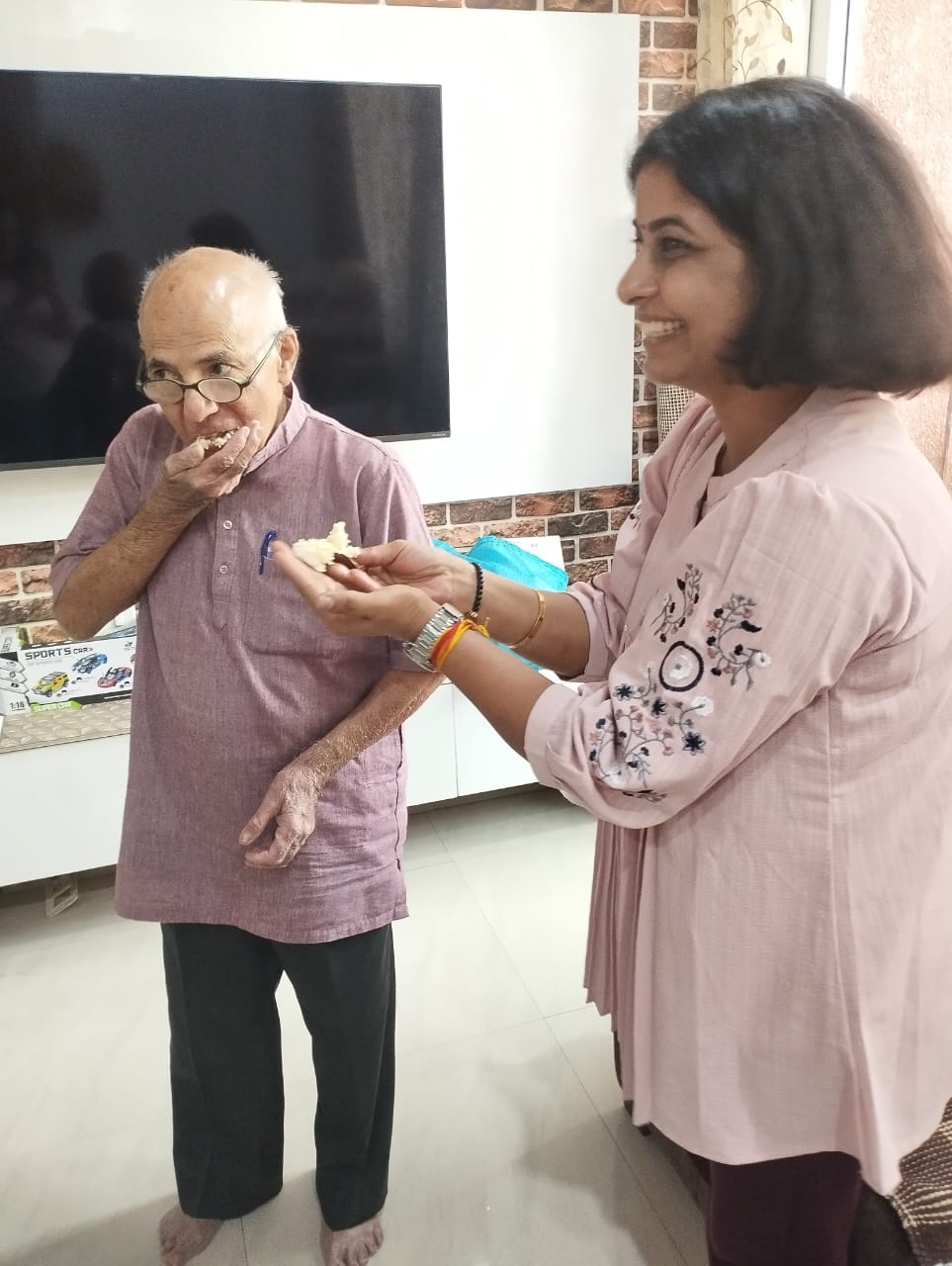 A student feeding cake to Prof. Gupta at his home.