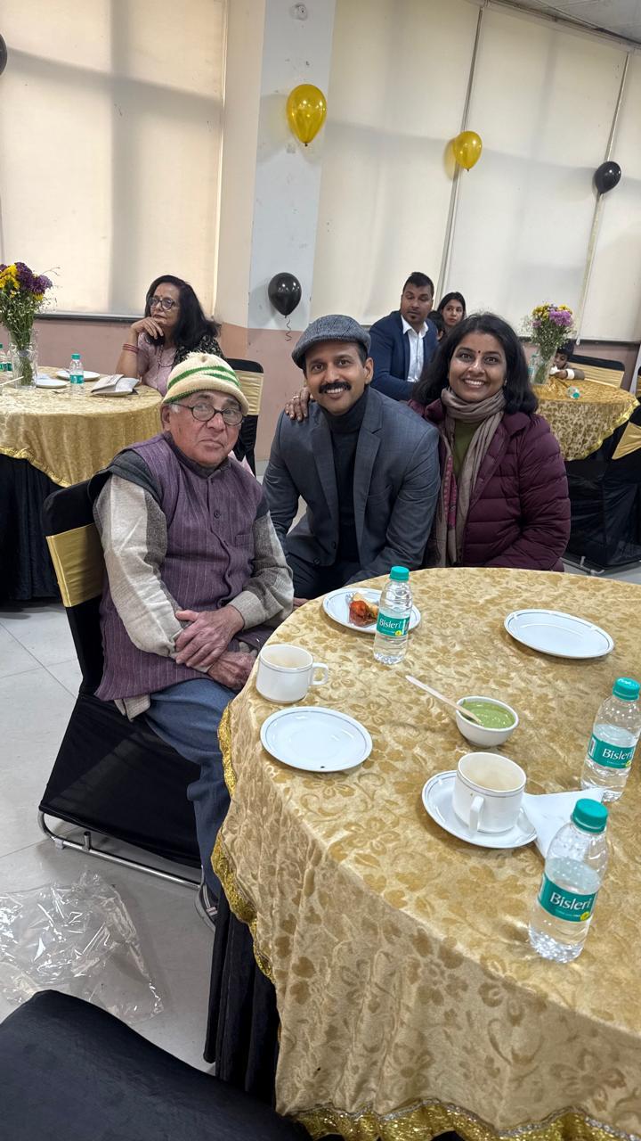Prof. Gupta in a winter cap, seated at a banquet table with former students.